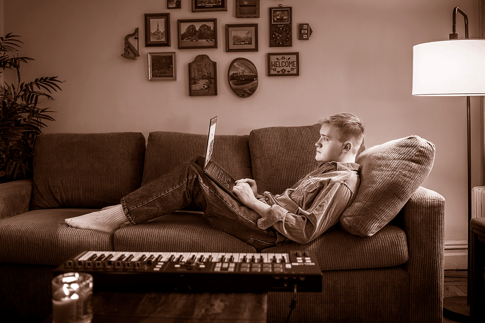 Jess, an adult living with muscular dystrophy, sitting on his couch composing music