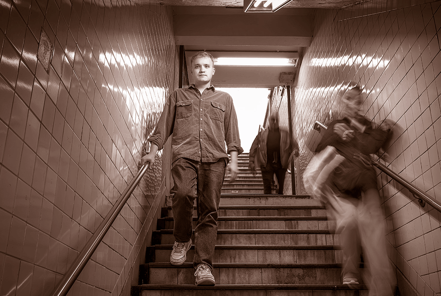 Jess, an adult living with muscular dystrophy, walking down the stairs to the subway